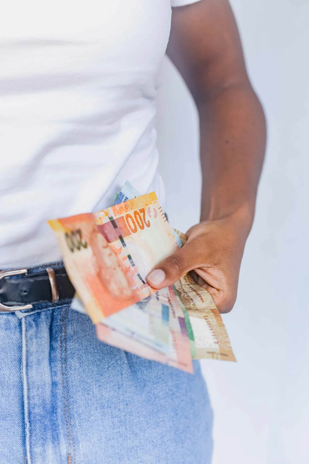 A person holding south african rands in their hand